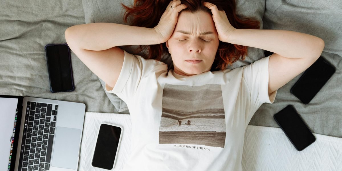 A person appears overwhelmed by multiple open screens, symbolizing the frustration of managing fragmented cloud workflows across many tools.