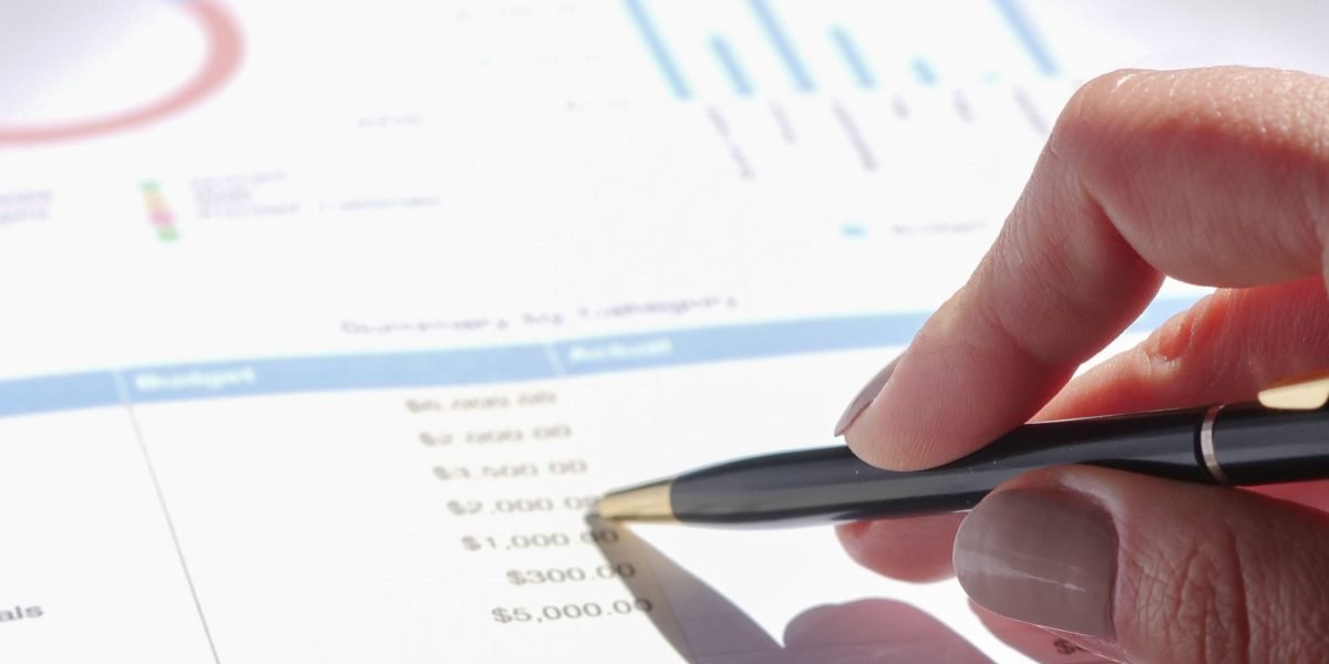 A focused individual reviewing a financial report, analyzing costs and budget allocations.