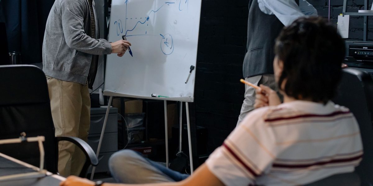 A team of professionals collaborating, discussing and problem-solving at a whiteboard, reflecting the challenges of technical debt.